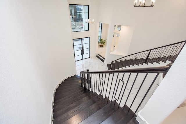 stairway featuring a towering ceiling and a chandelier