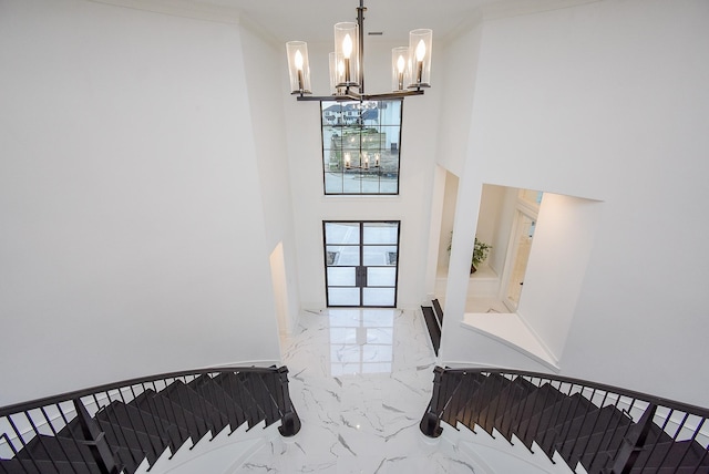 staircase with a notable chandelier, a towering ceiling, and french doors