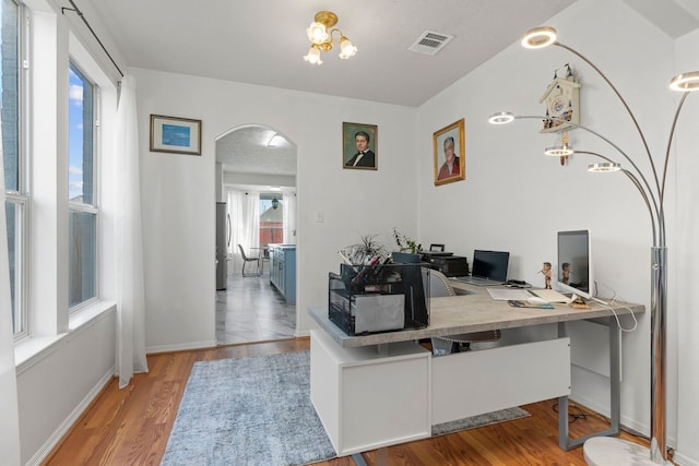 home office with light hardwood / wood-style floors and a chandelier