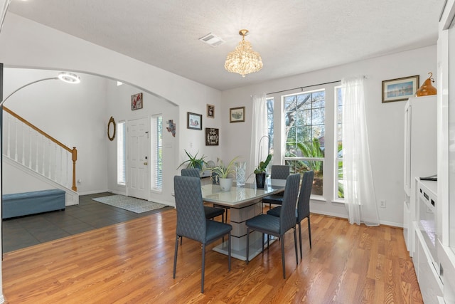 dining room with dark hardwood / wood-style flooring, a textured ceiling, and an inviting chandelier