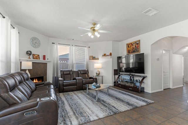 tiled living room with a textured ceiling, a tile fireplace, and ceiling fan