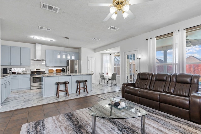 living room with ceiling fan, sink, and a textured ceiling