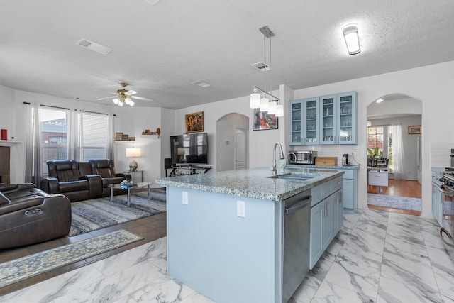 kitchen with sink, dishwasher, a textured ceiling, a center island with sink, and decorative light fixtures