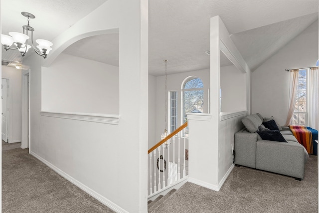 corridor featuring lofted ceiling, carpet, and a notable chandelier