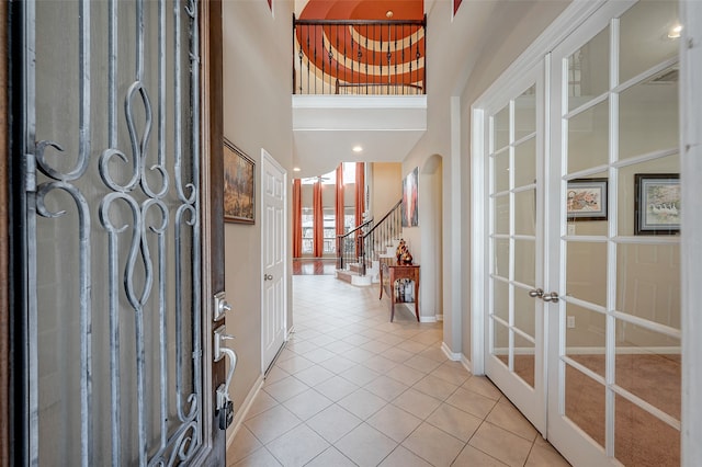 entrance foyer featuring a high ceiling, light tile patterned floors, and french doors