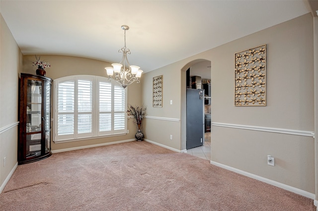 spare room with lofted ceiling, light colored carpet, and an inviting chandelier