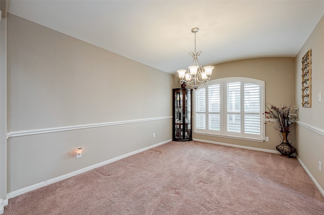 carpeted empty room with an inviting chandelier and lofted ceiling