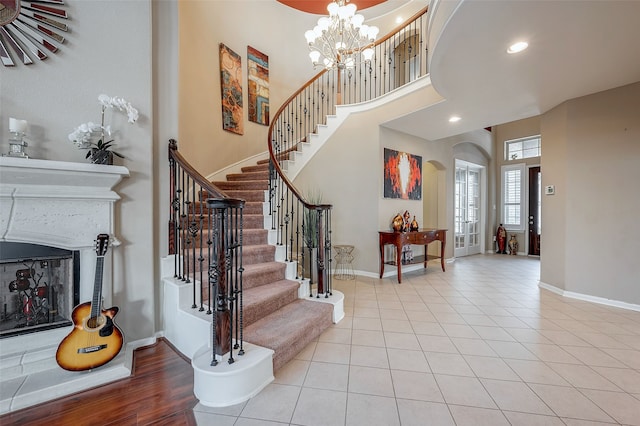 entryway featuring a towering ceiling, light tile patterned floors, and an inviting chandelier