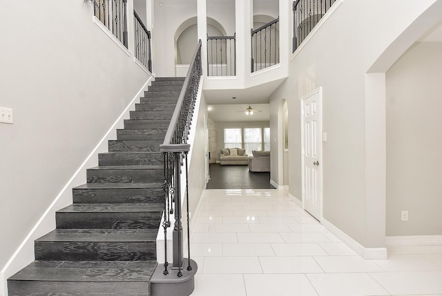 tiled foyer entrance with ceiling fan and a towering ceiling