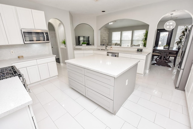 kitchen with sink, appliances with stainless steel finishes, hanging light fixtures, a center island, and white cabinets