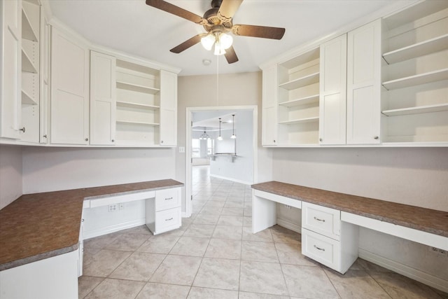 unfurnished office with built in desk, ceiling fan, and light tile patterned floors