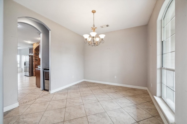 spare room featuring an inviting chandelier and light tile patterned floors