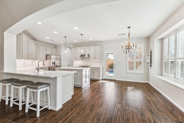 kitchen featuring appliances with stainless steel finishes, decorative light fixtures, white cabinetry, sink, and kitchen peninsula