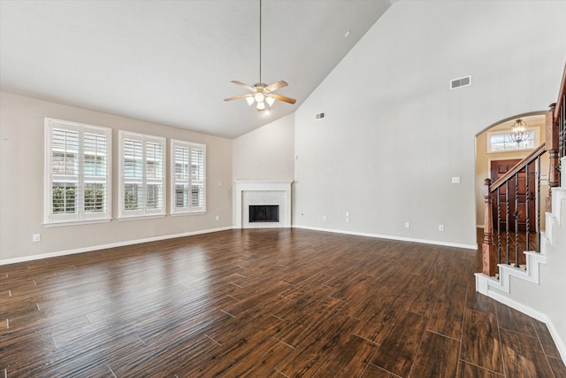 unfurnished living room featuring dark wood-type flooring, ceiling fan, a high end fireplace, and a wealth of natural light