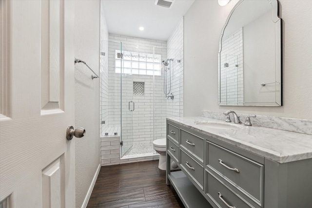 bathroom with vanity, hardwood / wood-style flooring, a shower with shower door, and toilet