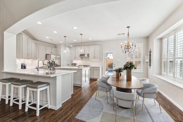 kitchen featuring stainless steel refrigerator, decorative light fixtures, white cabinetry, dark hardwood / wood-style flooring, and kitchen peninsula