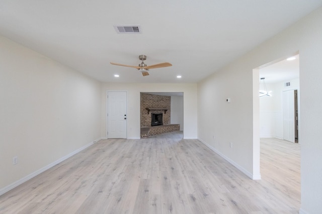 unfurnished living room with ceiling fan, a brick fireplace, and light wood-type flooring