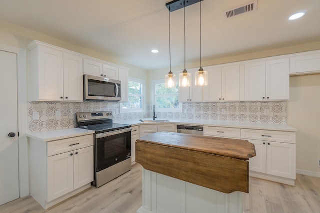 kitchen with pendant lighting, stainless steel appliances, sink, and white cabinets