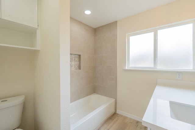 full bathroom with vanity, hardwood / wood-style flooring, tiled shower / bath combo, and toilet