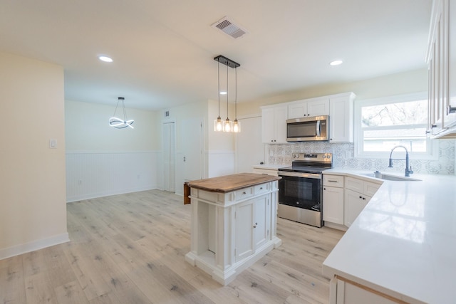 kitchen featuring appliances with stainless steel finishes, a center island, sink, and white cabinets