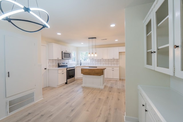 kitchen with white cabinetry, appliances with stainless steel finishes, a center island, and tasteful backsplash