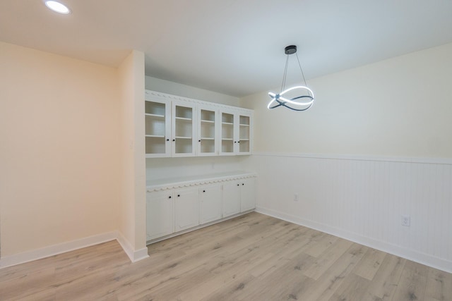 unfurnished dining area featuring an inviting chandelier and light wood-type flooring