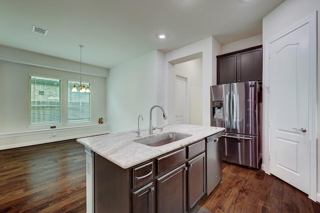 kitchen with sink, appliances with stainless steel finishes, dark hardwood / wood-style flooring, pendant lighting, and a kitchen island with sink