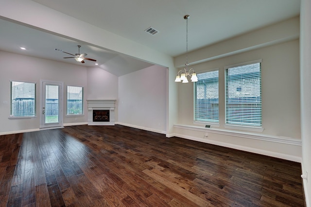 unfurnished living room with lofted ceiling, ceiling fan with notable chandelier, plenty of natural light, and dark hardwood / wood-style floors