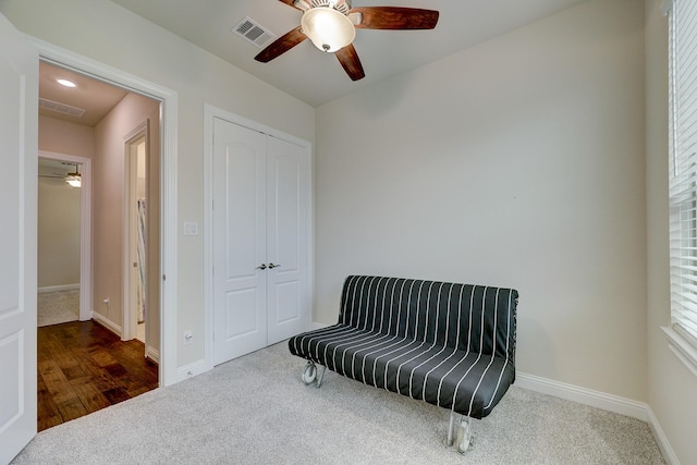 living area featuring ceiling fan and dark carpet