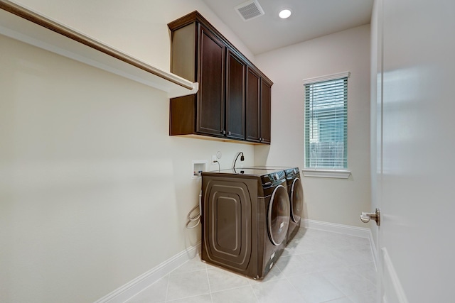 clothes washing area featuring light tile patterned flooring, cabinets, and washing machine and dryer