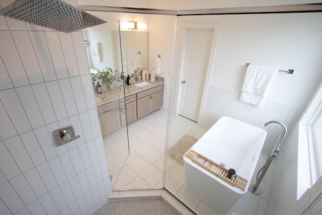 bathroom with walk in shower, tile patterned floors, vanity, and tile walls