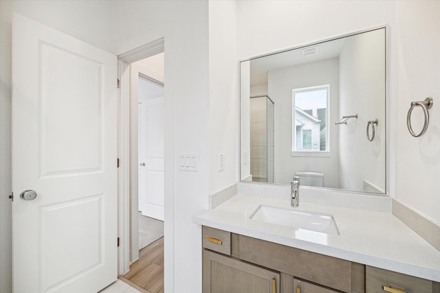 bathroom with vanity, toilet, wood-type flooring, and a shower