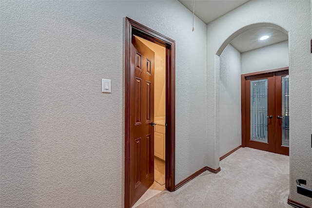 hallway with light colored carpet and french doors