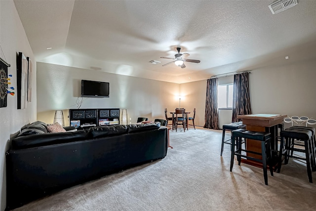 living room featuring ceiling fan, carpet floors, and a textured ceiling