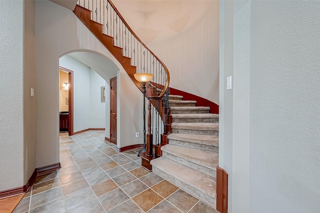 12403 Summer Lake Ranch Dr, Houston, TX 77044 - stairs featuring a high ceiling, arched walkways, and baseboards