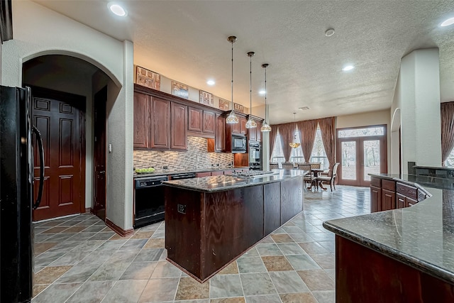 kitchen featuring decorative light fixtures, a center island, a textured ceiling, decorative backsplash, and black appliances