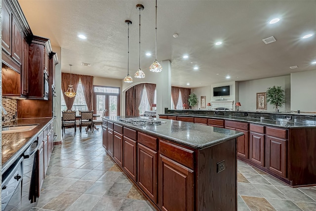 kitchen with pendant lighting, backsplash, dark stone counters, a center island, and black appliances