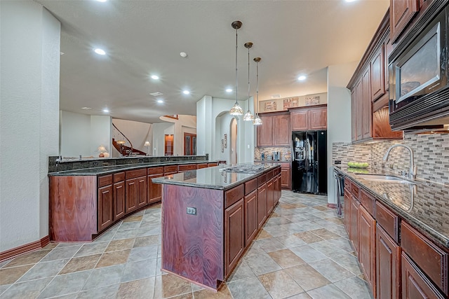 kitchen featuring sink, a center island, tasteful backsplash, black appliances, and decorative light fixtures