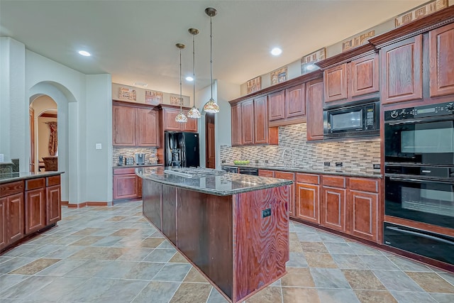 kitchen featuring pendant lighting, tasteful backsplash, dark stone counters, a center island, and black appliances