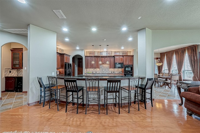 kitchen featuring a breakfast bar, kitchen peninsula, tasteful backsplash, lofted ceiling, and black appliances