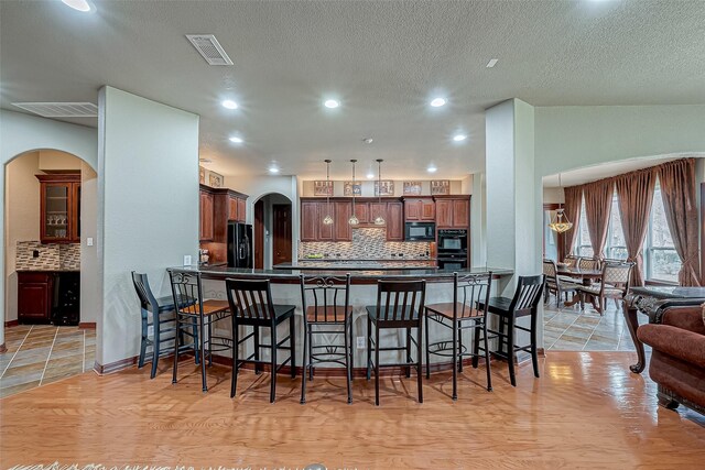 12403 Summer Lake Ranch Dr, Houston, TX 77044 - kitchen featuring a peninsula, dark countertops, arched walkways, black appliances, and a kitchen breakfast bar