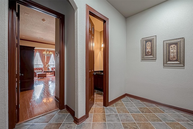 hall with an inviting chandelier, tile patterned floors, and a textured ceiling