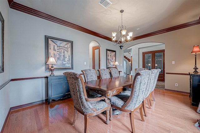 dining area featuring crown molding, a notable chandelier, and light wood-type flooring