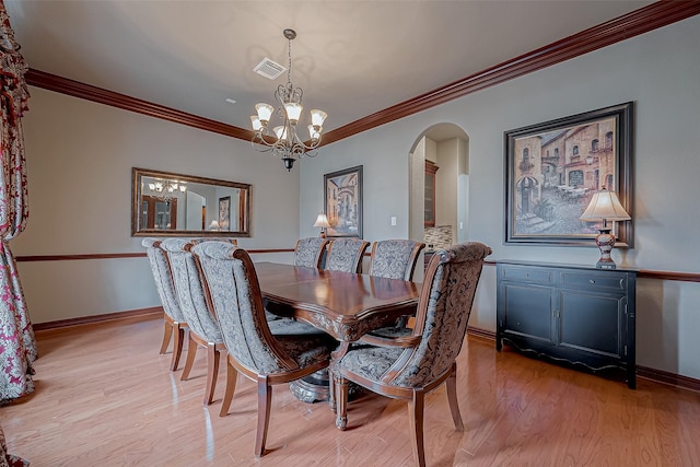 dining area with ornamental molding, a notable chandelier, and light hardwood / wood-style floors