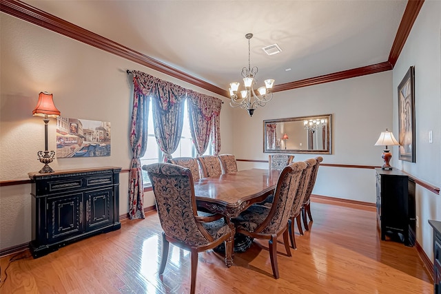 dining area featuring ornamental molding, light hardwood / wood-style floors, and a notable chandelier