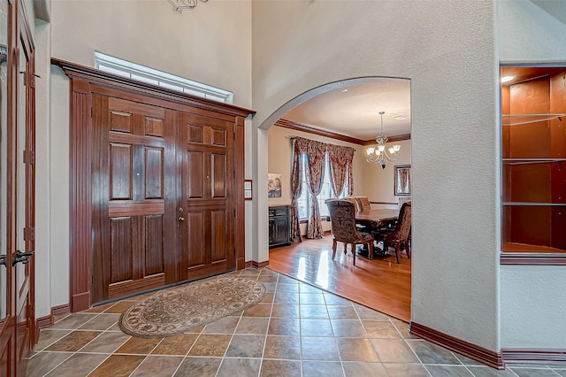 12403 Summer Lake Ranch Dr, Houston, TX 77044 - entryway featuring tile patterned floors, a notable chandelier, a high ceiling, baseboards, and arched walkways