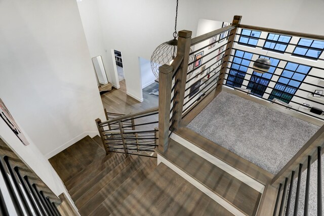 stairs with hardwood / wood-style flooring and a towering ceiling