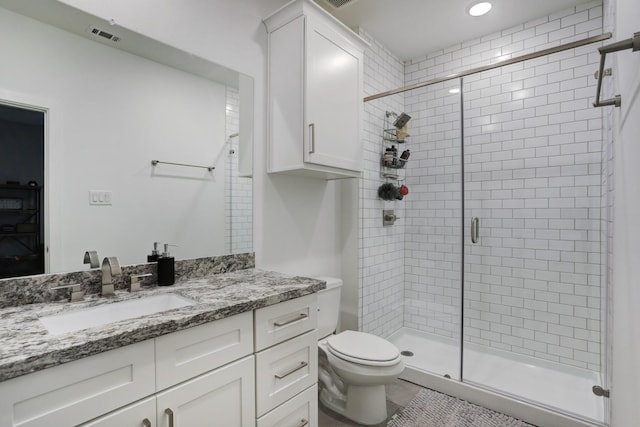 bathroom with vanity, toilet, and a shower with door