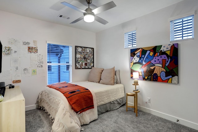 carpeted bedroom featuring multiple windows and ceiling fan