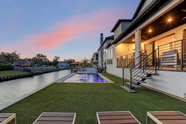 yard at dusk featuring a fenced in pool, a patio area, and a water view